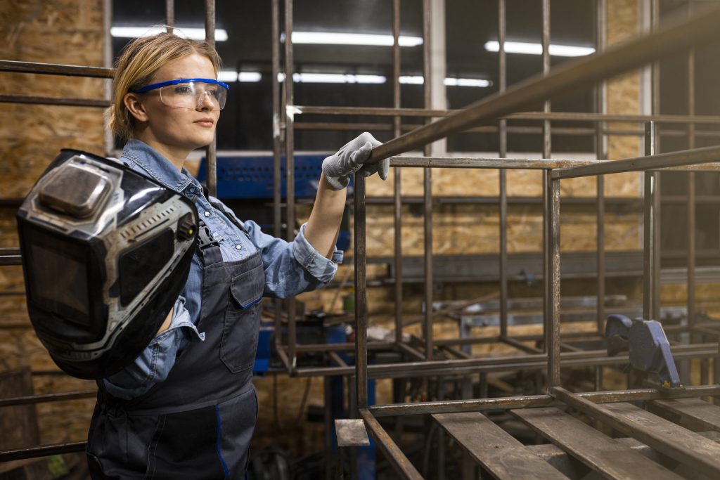 Kobieta spawacz podczas pracy w zakładzie produkcji wyrobów metalowych – precyzyjne łączenie elementów stalowych