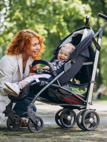 matka nachyla się nad swoim dzieckiem w wózeczku