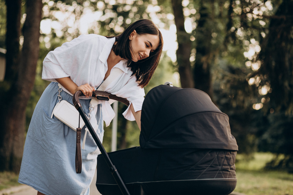 kobieta pochylająca się nad spacerowym wózkiem dziecięcym z gondolą