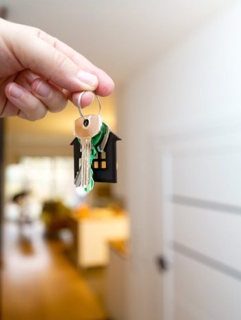 dłoń trzymająca klucze na tle sprzedanego do skupu mieszkania